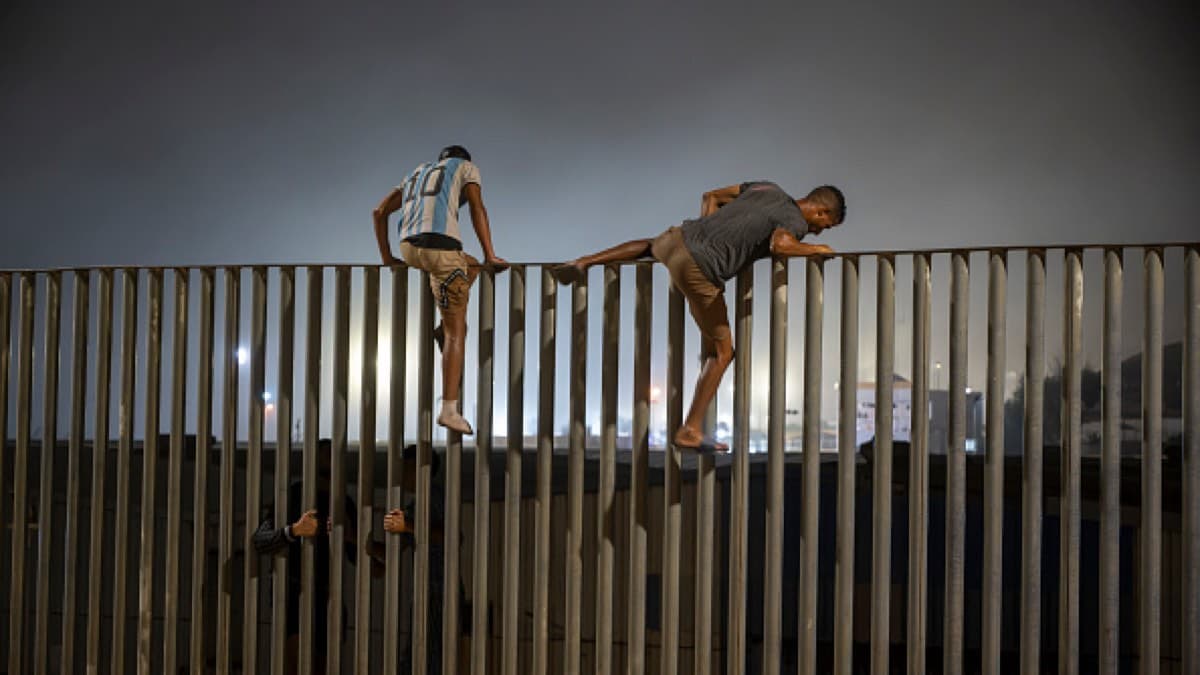 Migrants climbing over a border fence at night near Spain's enclave of Ceuta