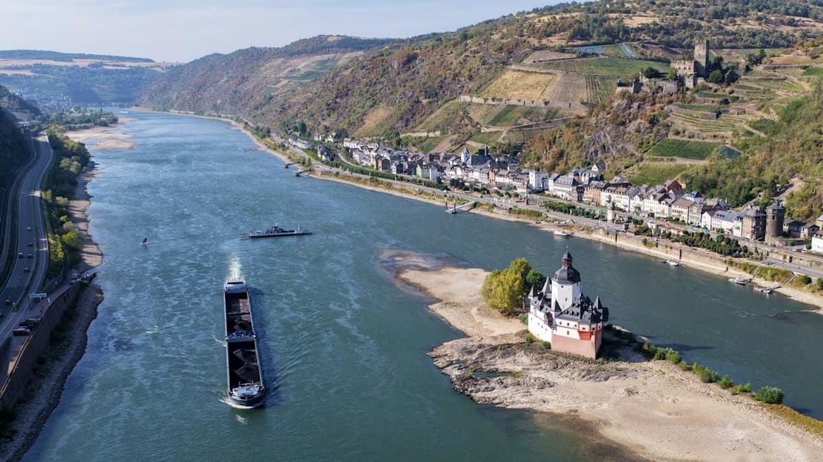 A cargo barge on the Rhine at low water with exposed sandbanks and a castle near Kaub
