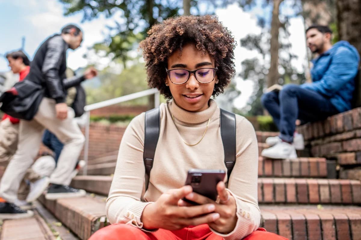 A young woman uses a smartphone while sitting on outdoor steps