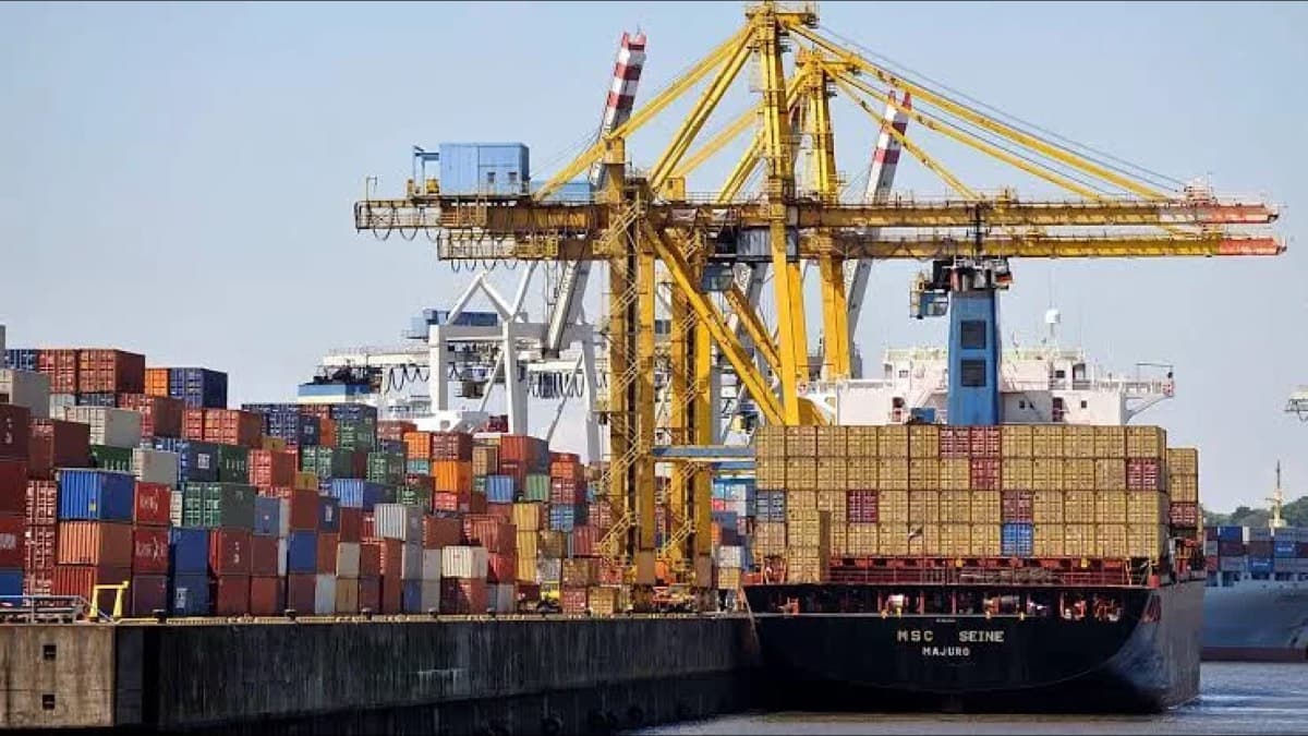 A container ship being loaded at a port with cranes and stacked shipping containers