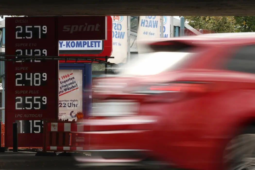 A fuel price board and passing car at a German gas station as pump prices spike