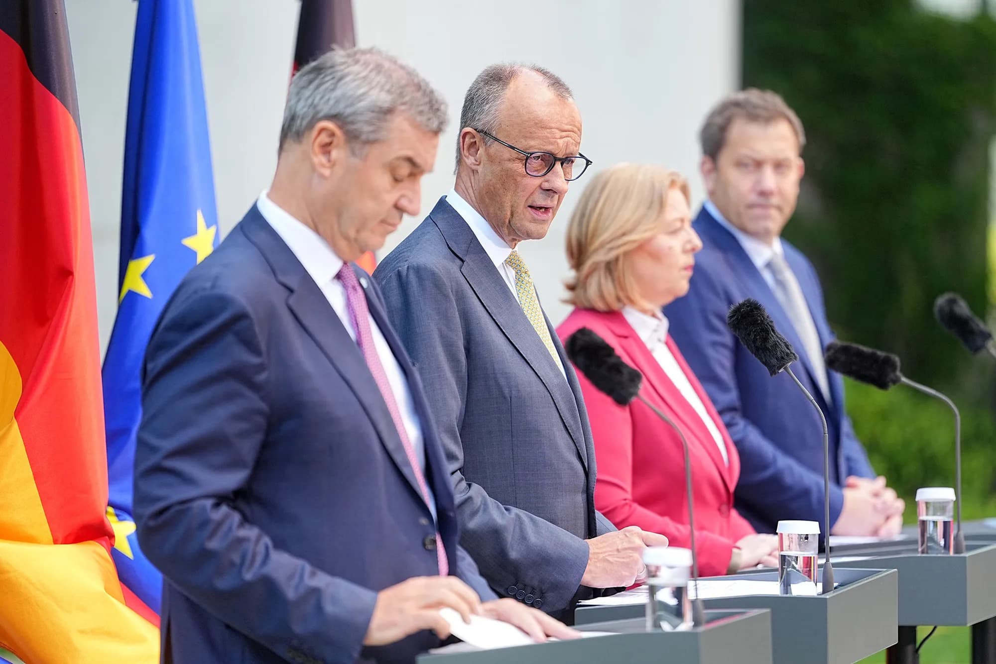 German coalition leaders including Friedrich Merz speak at a news conference in front of German and EU flags