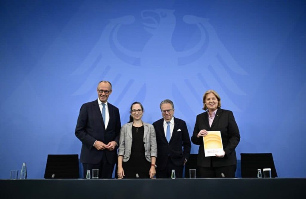German officials present a report at a news conference in front of the federal eagle emblem