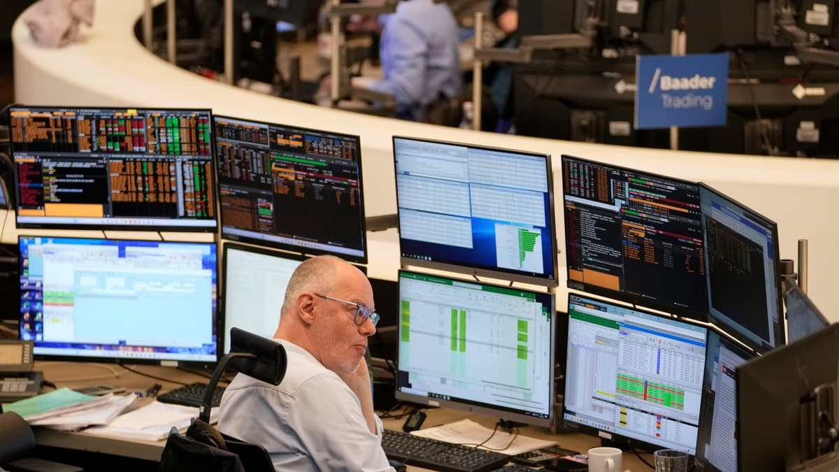 A trader at the Frankfurt stock exchange surrounded by monitors showing market data