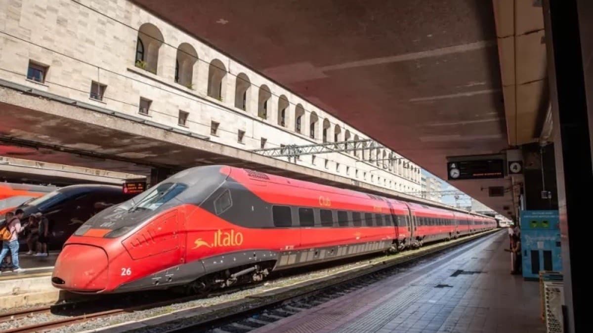 A red Italo high speed train waiting at a station platform