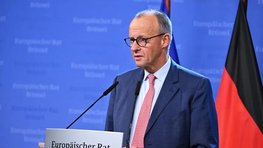 German Chancellor Friedrich Merz speaking at a podium during a European Council press appearance