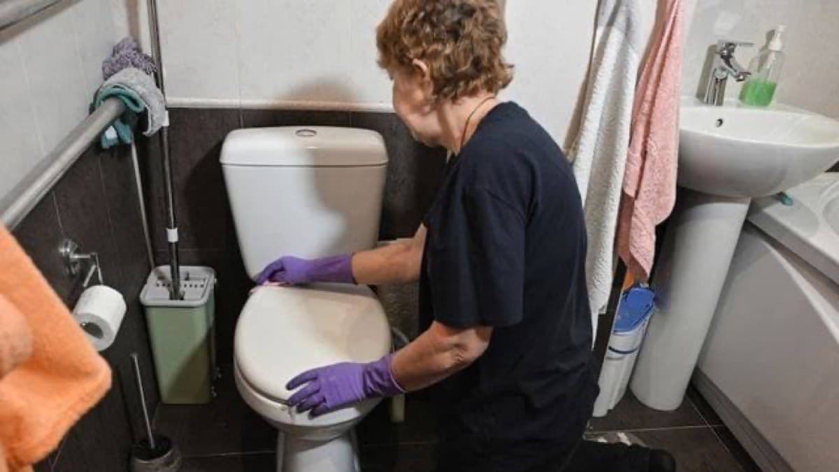 A domestic worker in rubber gloves cleaning a bathroom, a role often held on a minijob contract