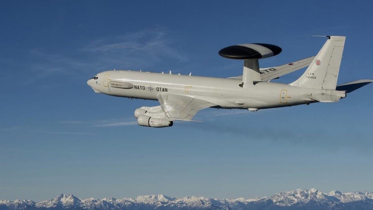 NATO Boeing E-3 Sentry AWACS aircraft with its radar rotodome in flight above a snow capped mountain range