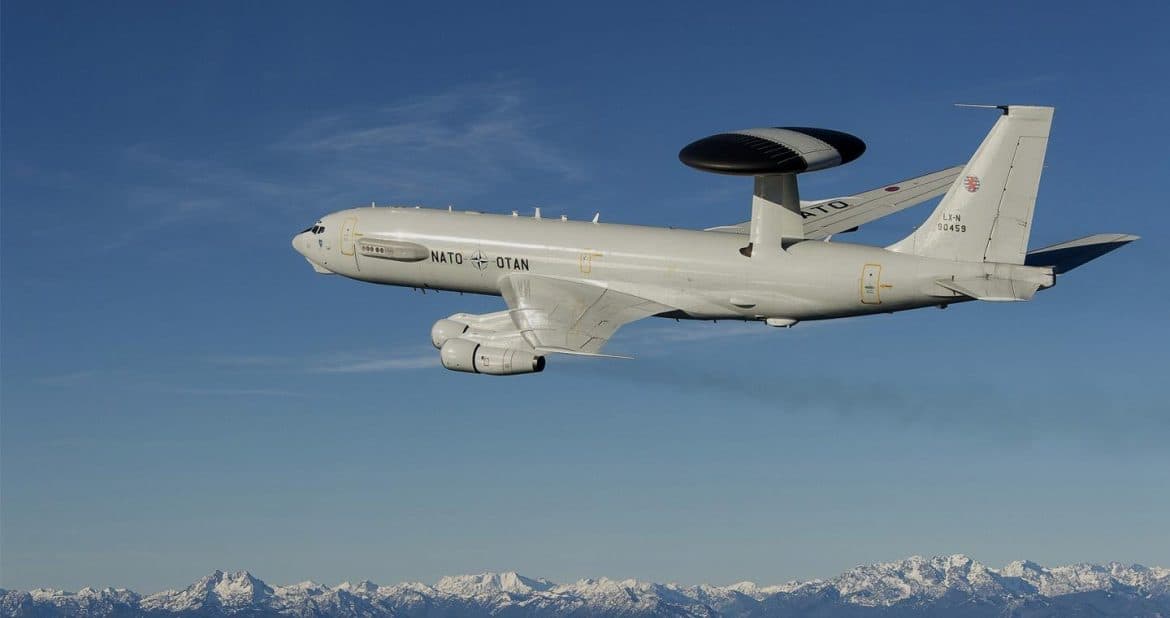 NATO Boeing E-3 Sentry AWACS aircraft with its radar rotodome in flight above a snow capped mountain range