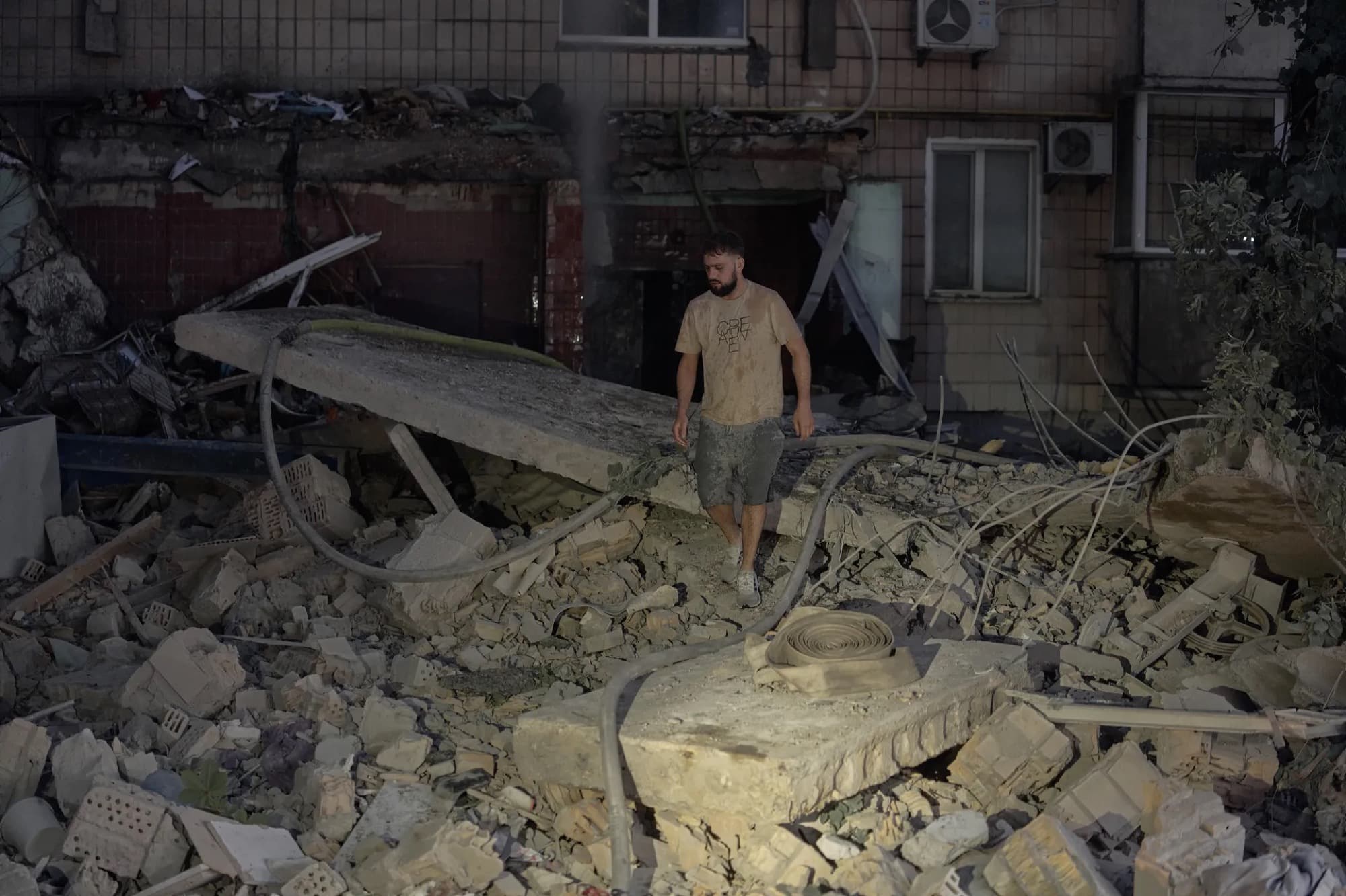 A man walks through the rubble of a residential building in Kyiv destroyed by a Russian strike