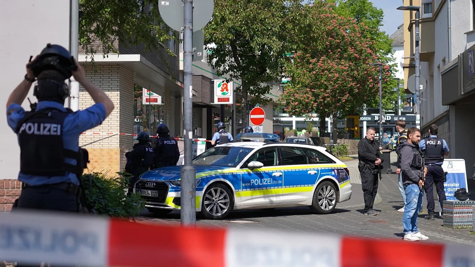 Armed German police officers and a patrol car cordon off a street with red and white tape after a shooting