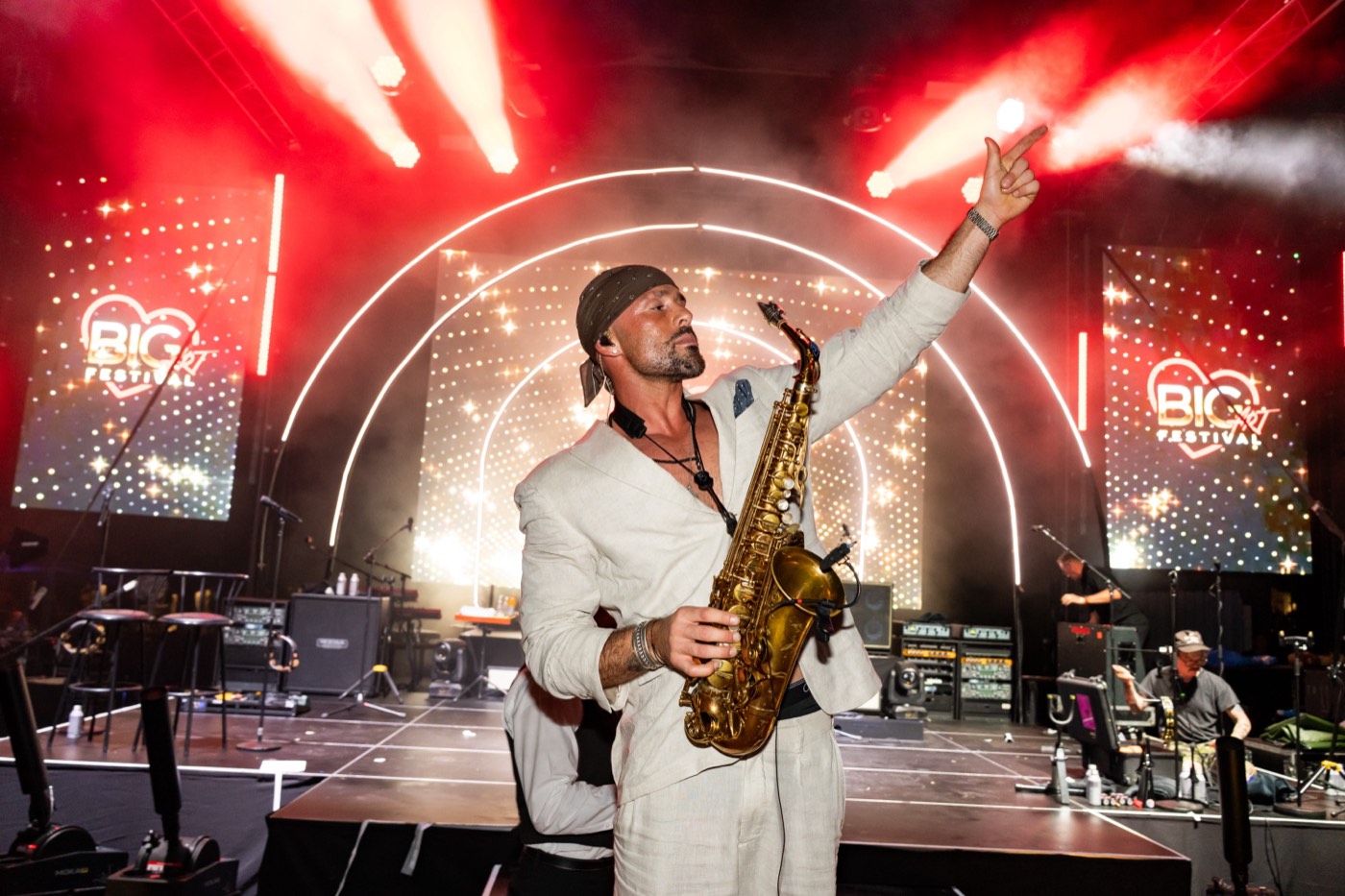 A saxophonist in a white suit performing on the BIG ART Festival stage