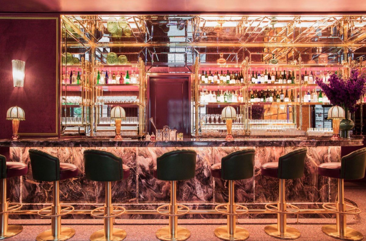 The mirrored bar at Two E Bar and Lounge inside The Pierre, with green velvet stools and warm lighting
